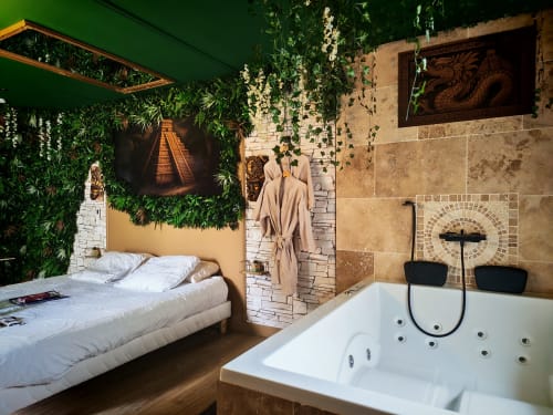 Suite Romance luxueuse à L'expérience hotel à L'Etrat avec bain à remous, lit et murs tropicaux verdoyants