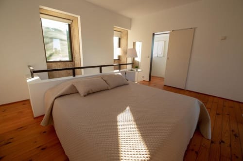Quarto luminoso na Quinta da Malaposta Boutique Hotel com cama queen, assoalho em madeira e vista para a piscina