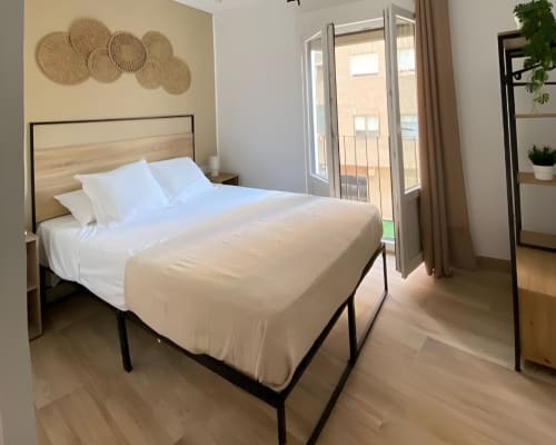 Moderno dormitorio en Grampy Boutique Hostal con cama queen, arte tejido en la pared y acceso a balcón