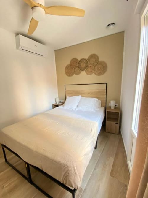 Acogedora habitación doble estándar en Grampy Boutique Hostal con dos camas, cabeceros de madera y cestas decorativas en la pared