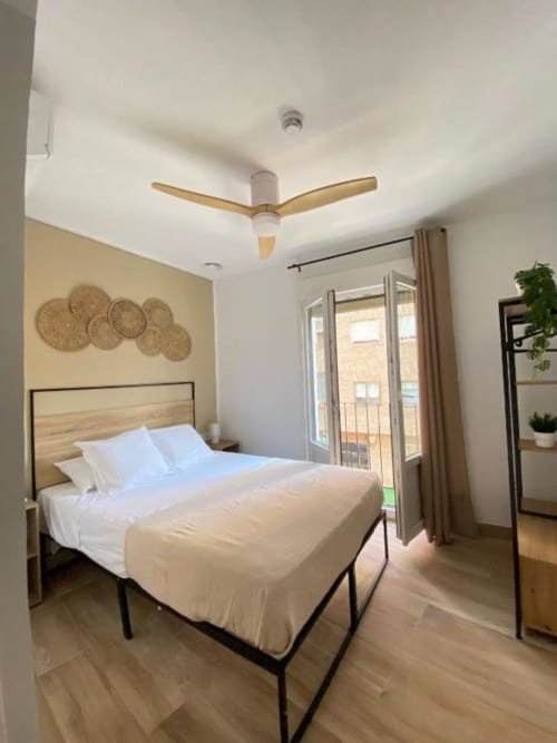 Habitación doble estándar luminosa en Grampy Boutique Hostal con vistas a la ciudad, cama de madera, ventilador de techo y acceso a balcón