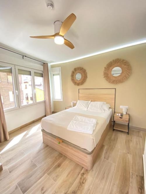 Habitación Superior moderna en Grampy Boutique Hostal con cama de madera, ventilador de techo, luz natural y vistas a la ciudad en España