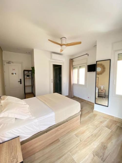 Habitación superior moderna en Grampy Boutique Hostal con cama matrimonial, ventilador de techo, pisos de madera y vista a la ciudad