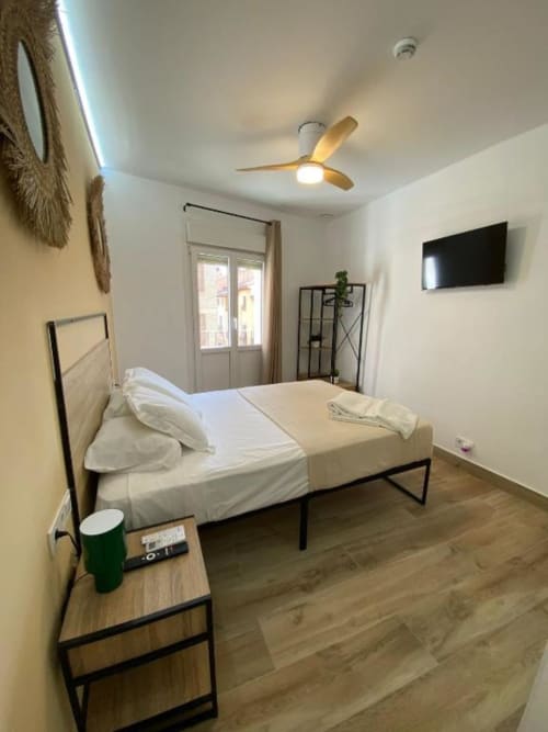 Habitación superior moderna en Grampy Boutique Hostal con cama, ventilador de techo, TV y vistas a la ciudad desde el balcón