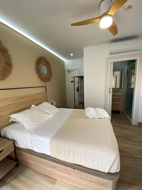 Habitación moderna de lujo en Grampy Boutique Hostal en España con cama de madera, ventilador de techo y baño privado