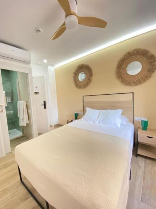 Moderno dormitorio de hotel en Grampy Boutique Hostal con cama, ventilador de techo, espejos tejidos y baño privado