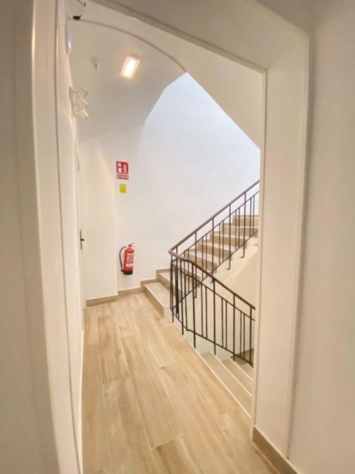 Escalera del Grampy Boutique Hostal con barandilla metálica, extintor y claraboya en Madrid
