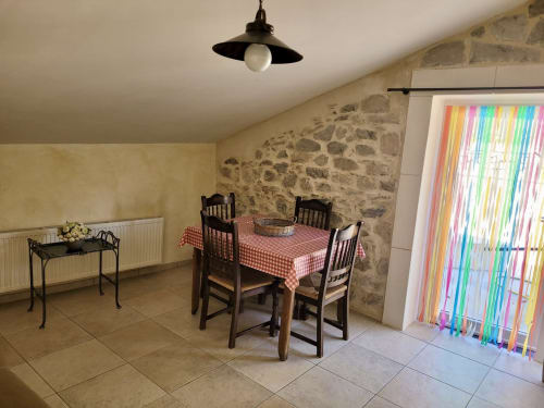 Salle à manger du Gîte de la Source, Domaine de la Méouge à Barret-sur-Méouge aux murs de pierre et rideaux colorés