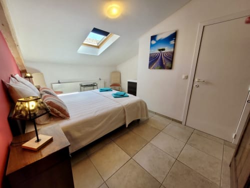 Chambre mansardée lumineuse au gîte Domaine de la Méouge avec puits de lumière, décor champ de lavande et lit confortable turquoise