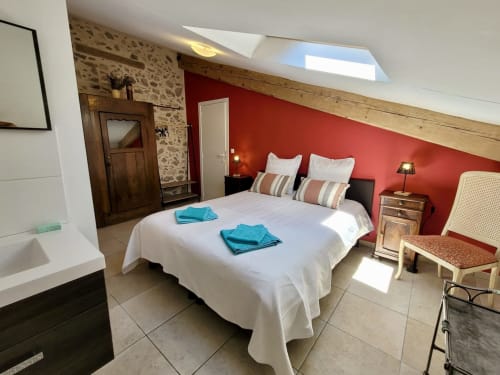 Chambre spacieuse au Domaine de la Méouge avec mur accent rouge, puits de lumière, literie blanche et accès vue montagne