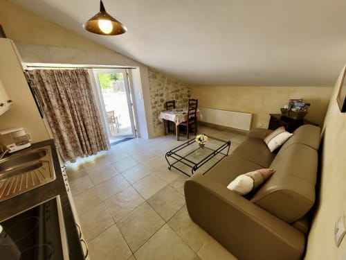 Salon douillet du Domaine de la Méouge avec canapé beige, salle à manger et accès à la terrasse à Barret-sur-Méouge