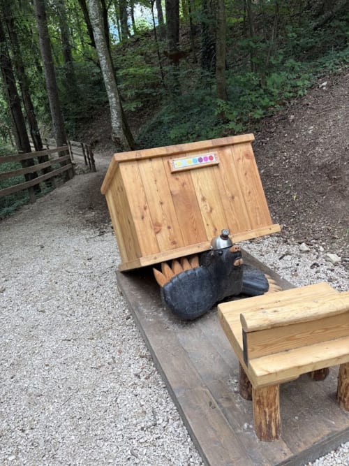 Scultura in legno di orso all'ingresso del sentiero Affittacamere Mercedes a Romallo, zona turistica di montagna in Italia