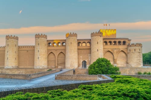 Castillo medieval fortificado con bandera amarilla y foso en España, monumento arquitectónico cerca de Grampy Boutique Hostal