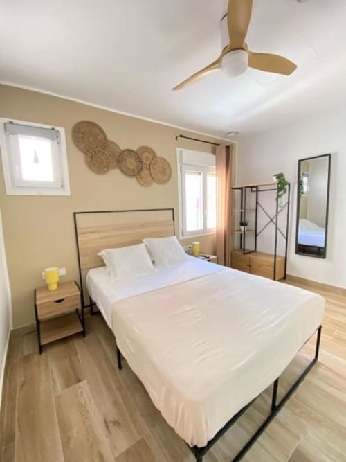 Habitación luminosa en Grampy Boutique Hostal con camas gemelas, piso de madera, ventilador de techo y paredes beige con decoración tejida