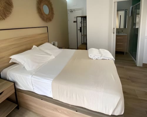 Habitación deluxe en Grampy Boutique Hostal con cama tendida, muebles de madera y baño privado