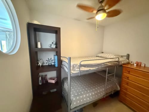 Acogedora habitación en apartamento de Fuengirola con literas, cómoda de madera, estantería, ventilador de techo y espejo redondo