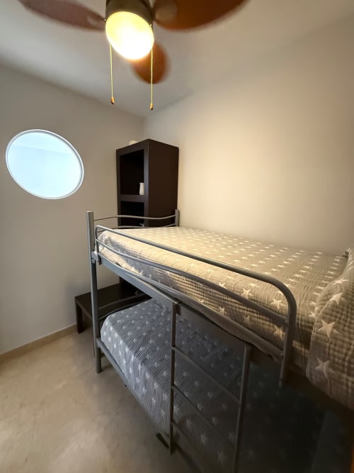 Litera en dormitorio luminoso del Grupo Inmo House, Fuengirola con ventana redonda y lámpara de techo