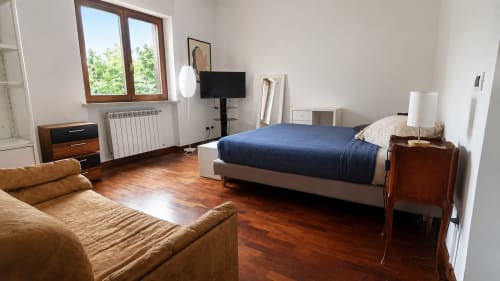 Ampia camera da letto a Roma con letto, divano in pelle marrone, pavimenti in legno e vista sulla città presso l'hotel Myob
