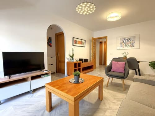 Moderno apartamento frente al mar en Fuengirola con salón, muebles de madera y vistas a la ciudad