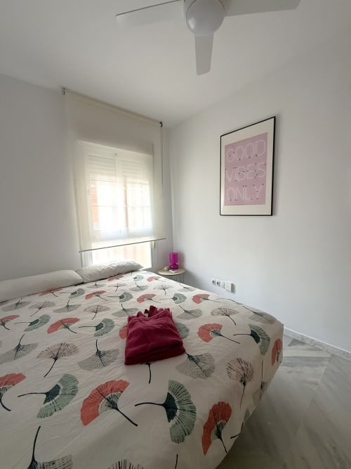 Dormitorio luminoso en apartamento frente al mar de Grupo Inmo House en Fuengirola con ropa de cama estampada y ventilador de techo moderno