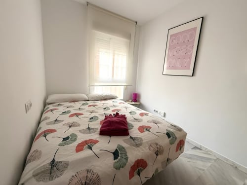 Dormitorio acogedor en apartamento frente al mar, Fuengirola. Ropa de cama floral, luz natural, decoración moderna.