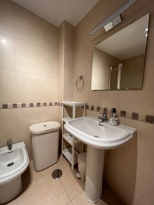 Baño moderno con lavamanos de pedestal, inodoro y almacenamiento en apartamento de playa en Fuengirola