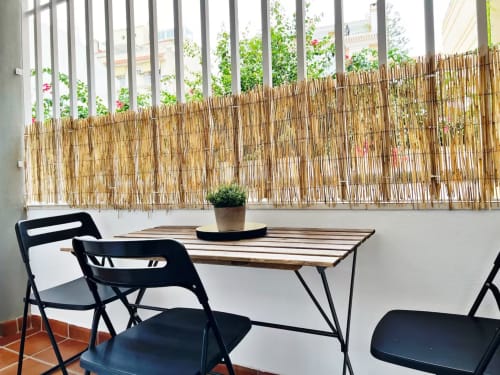 Terraza moderna del apartamento de playa en Fuengirola con sillas plegables, mesa de madera y vistas a la ciudad, biombo de caña natural