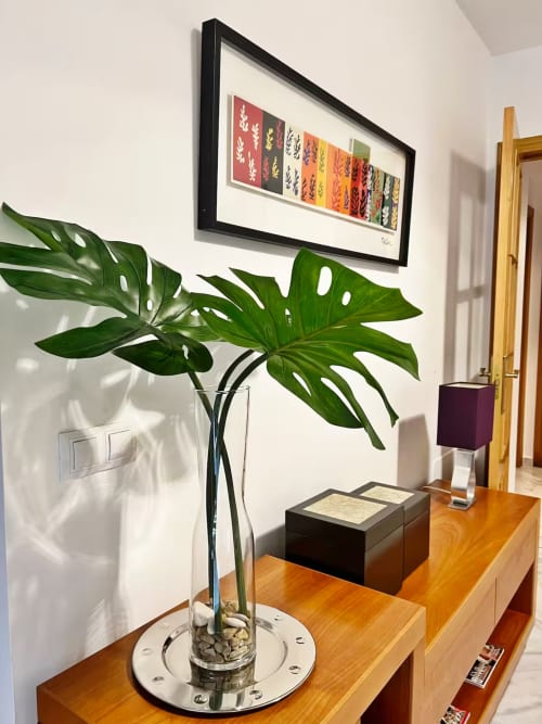 Recibidor moderno con planta Monstera, arte botánico colorido y muebles de madera en primera línea de playa de Fuengirola