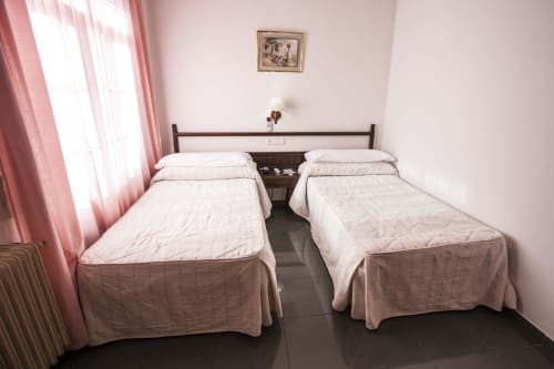 Habitación doble con dos camas individuales en Hostal Venta del Sol en Baza, con cortinas rosas y comodidades modernas