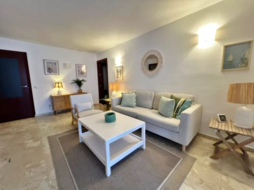 Amplio salón en apartamento de Fuengirola con sofá gris, mesa de café blanca y mobiliario moderno por Grupo Inmo House