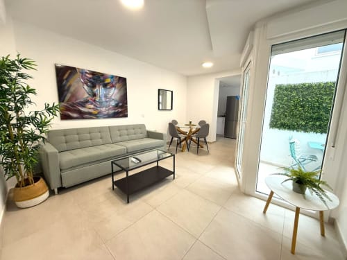 Luminoso apartamento en Fuengirola con sofá gris, comedor y acceso a terraza en Grupo Inmo House