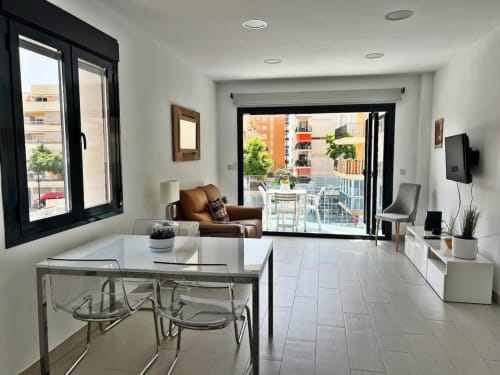 Apartamento de lujo moderno en Fuengirola con mesa de comedor, sillón marrón, acceso a terraza y vistas a la ciudad