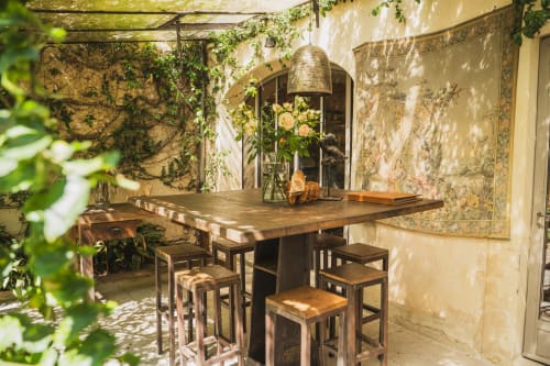 Cour rustique des Jardins de Baracane à Avignon avec comptoir en bois, tabourets de bar, lierre et murs de pierre vieillis