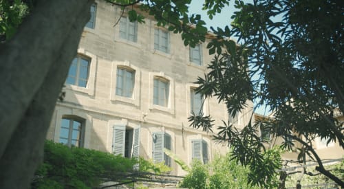 Bâtiment historique en pierre des Jardins de Baracane, gîte d'Avignon, recouvert de lierre et de verdure