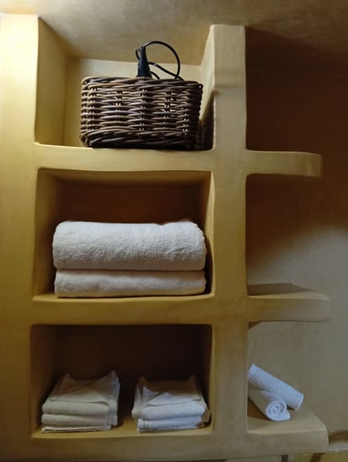 Étagères intégrées du Riad Le Village Mogador avec panier en osier, serviettes roulées et linge plié