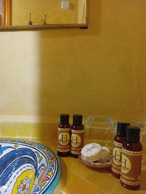 Articles de toilette du Riad Le Village Mogador à Essaouira avec poterie marocaine décorative et flacons de produits de marque