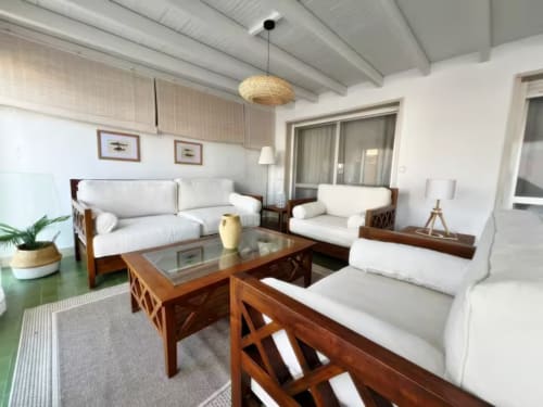 Amplio salón moderno en apartamento de Fuengirola con sofás blancos, muebles de madera y vistas a la ciudad desde la terraza.