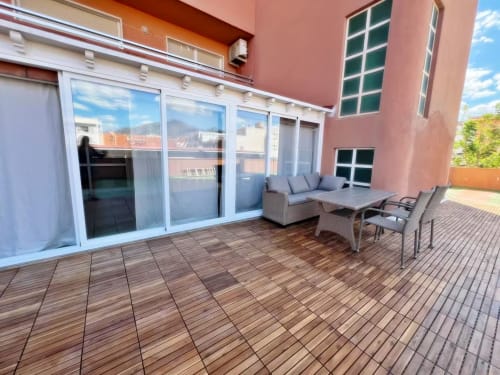 Amplio balcón de apartamento en Fuengirola con terraza de madera, zona de descanso y vistas a la ciudad, Grupo Inmo House