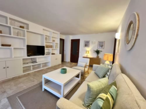 Espacioso apartamento en Fuengirola con salón moderno, estanterías blancas, sofá, TV y vistas a la terraza.