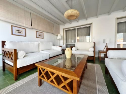 Amplio salón de apartamento en Fuengirola con muebles de madera, asientos tapizados en blanco, mesa de cristal y vistas a la ciudad