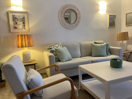 Moderno salón en Fuengirola con sofá gris, sillón y vistas a la ciudad - Grupo Inmo House