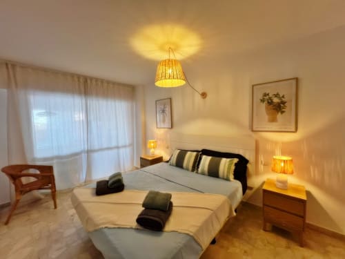 Amplio y luminoso apartamento dormitorio en Fuengirola con camas gemelas, iluminación cálida, vista a terraza y mobiliario moderno