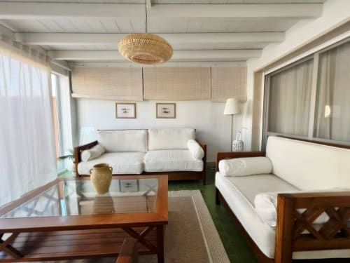 Amplio y luminoso salón de apartamento en Fuengirola con muebles de madera, sofás color crema y vistas a la ciudad desde la terraza