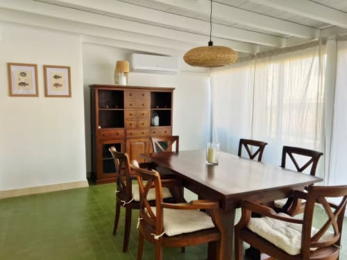 Amplio comedor en apartamento de Fuengirola con mesa de madera, sillas, mueble de almacenaje y luz natural desde la terraza