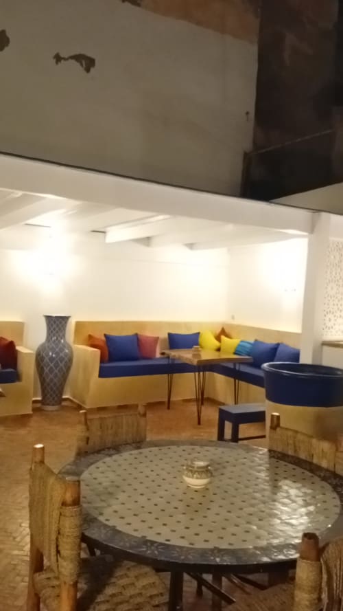 Salon Chambre Esprit Safran du Riad Le Village Mogador avec sièges bleus et jaunes, vase décoratif et table ronde