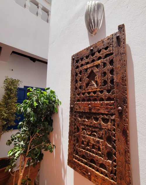 Panneau en bois sculpté orné de motifs complexes sur mur blanc au Riad Le Village Mogador à Essaouira