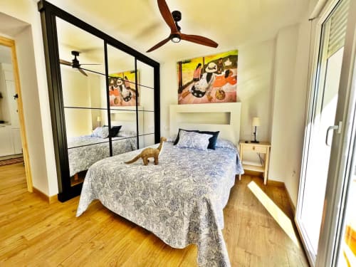 Dormitorio moderno en apartamento de playa en Fuengirola con cama dosel, suelos de madera y mobiliario contemporáneo