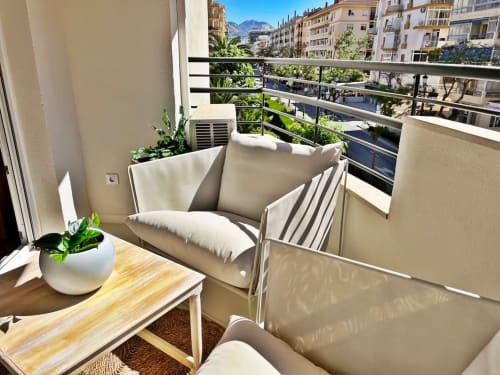 Apartamento moderno con balcón en Fuengirola, mobiliario beige, vistas a la ciudad, plantas en macetas y cordillera al fondo