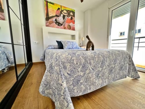 Moderno dormitorio en apartamento frente al mar, Fuengirola, con ropa de cama estampada, vista a la ciudad y mobiliario contemporáneo.