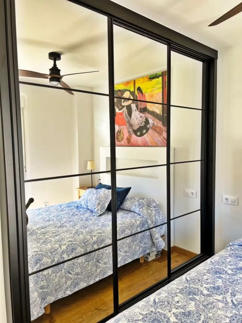 Dormitorio moderno en apartamento de playa en Fuengirola con armario espejo, ropa de cama azul estampada, ventilador de techo y colorido